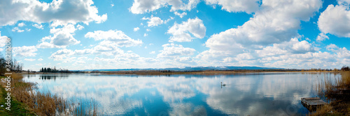 Fototapeta Naklejka Na Ścianę i Meble -  Panoramic landscape from the lake shore with colorful clouds in the spring sun.