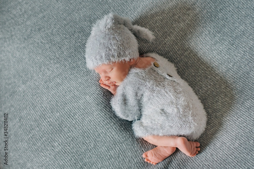 Newborn baby boy, 9 days old, sleeping and wrapped in a grey blanket, and in a grey background. photo