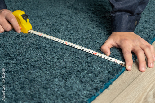 worker measures the carpet for restoration and cleaning.