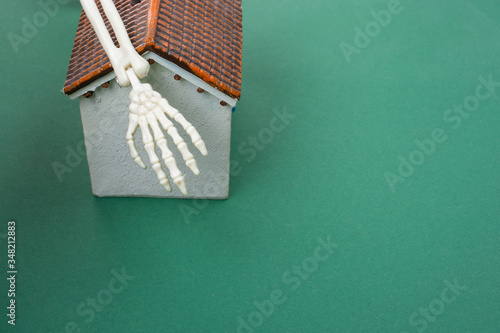 Small model housewith human skeleton hand on photo