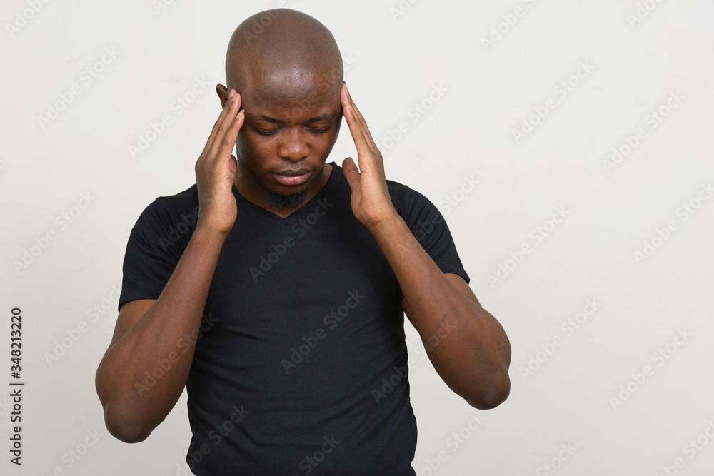 Naklejka premium Stressed young bald African man having headache