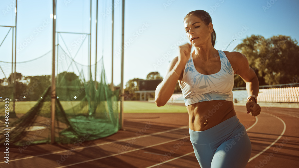 Beautiful Fitness Woman in Light Blue Athletic Top and Leggings Jogging in  the Stadium. She is Running Fast on a Warm Summer Afternoon. Athlete Doing  Her Routine Sports Practice. Stock Photo