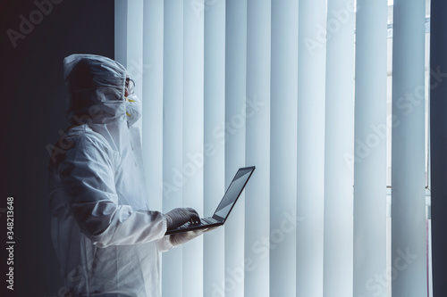 Medical worker in protective suit uses laptop