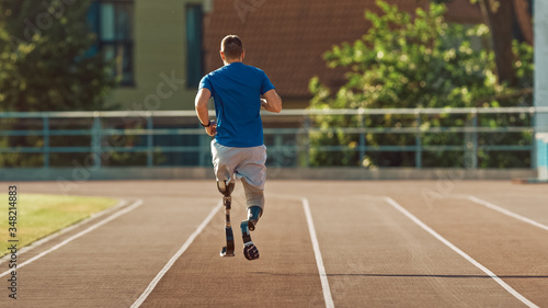 Athletic Disabled Fit Man with Prosthetic Running Blades is Training on a Outdoors Stadium on a Sunny Afternoon. Amputee Runner Jogging on a Stadium Track. Motivational Sports Shot.