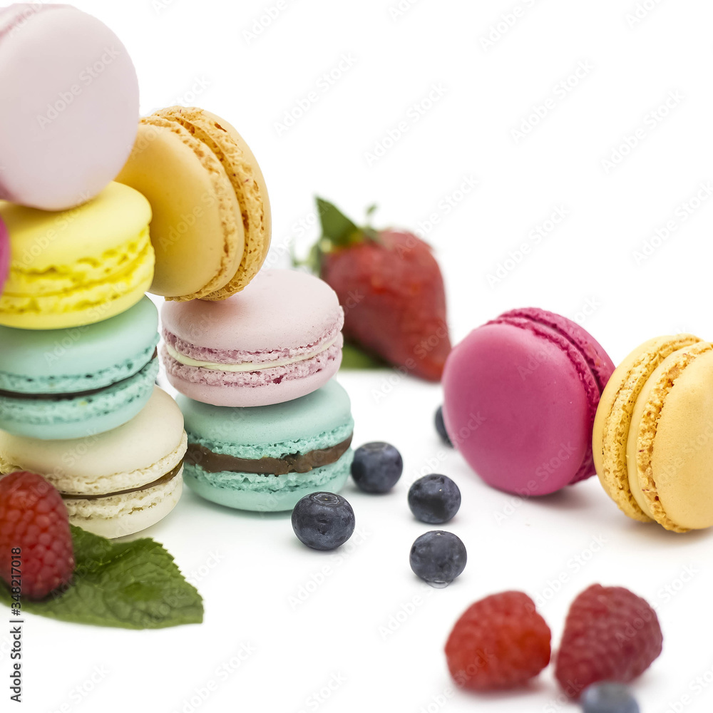 Multicolored macaroons on a white background with strawberries, raspberries, mint and blueberries Multicolored macaroons on a white background with strawberries, raspberries, mint and blueberries