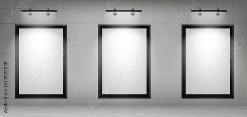 Blank movie posters illuminated by spotlights. Vector realistic mockup of white picture in black frames on gray tiled wall in cinema, theater hallway or gallery. Empty advertising banners with lamps