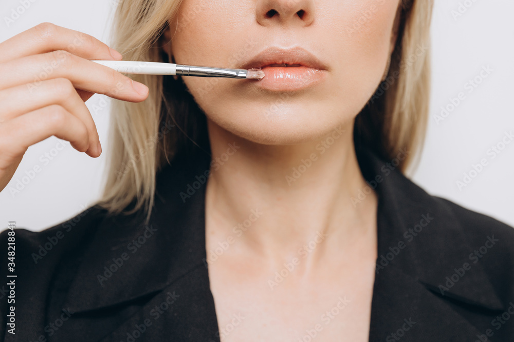 A pretty young woman is using different make-up accessories for application of make-up