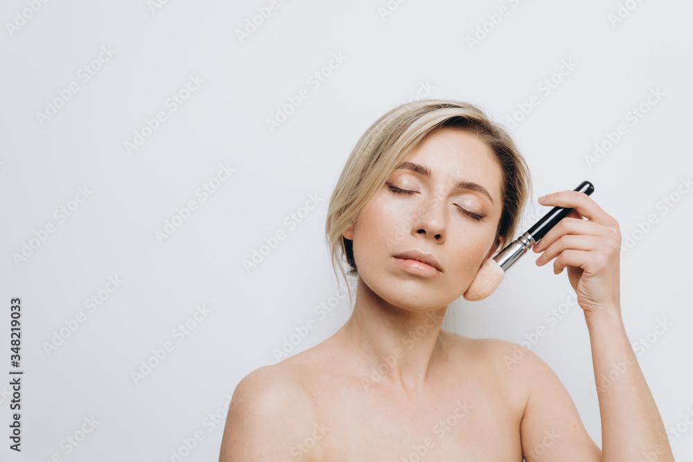 A pretty young woman is using different make-up accessories for application of make-up A pretty young woman is using different make-up accessories for application of make-up
