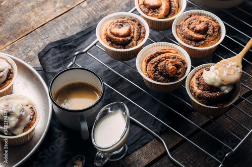 Cooking of homemade cakes. Sweet pastries on a wooden table with a cup of coffee and milk. Home Cinnabon. View from above. Rustic