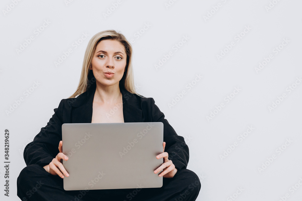 A beautiful young woman is sitting on the floor with a notebook pc on her lap, against a light background A beautiful young woman is sitting on the floor with a notebook pc on her lap, against a light background