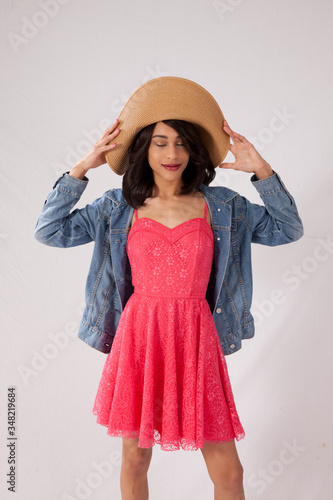 Happy Caucasian woman in a pink sun dress and a straw hat.