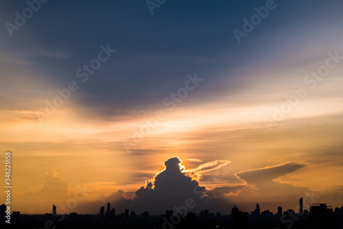 Silhouette cityscape and many buildings towers with beautiful sunset with twilight sky and cloud. sunset and light rays from clouds shining to sky. Heaven in nature.