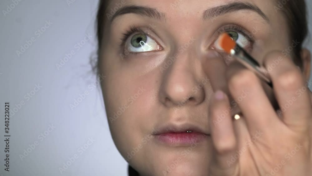 Make-up artist making professional make-up for young woman in beauty studio. Make up Artist applies concealer on eyes area Make-up artist making professional make-up for young woman in beauty studio. Make up Artist applies concealer on eyes area