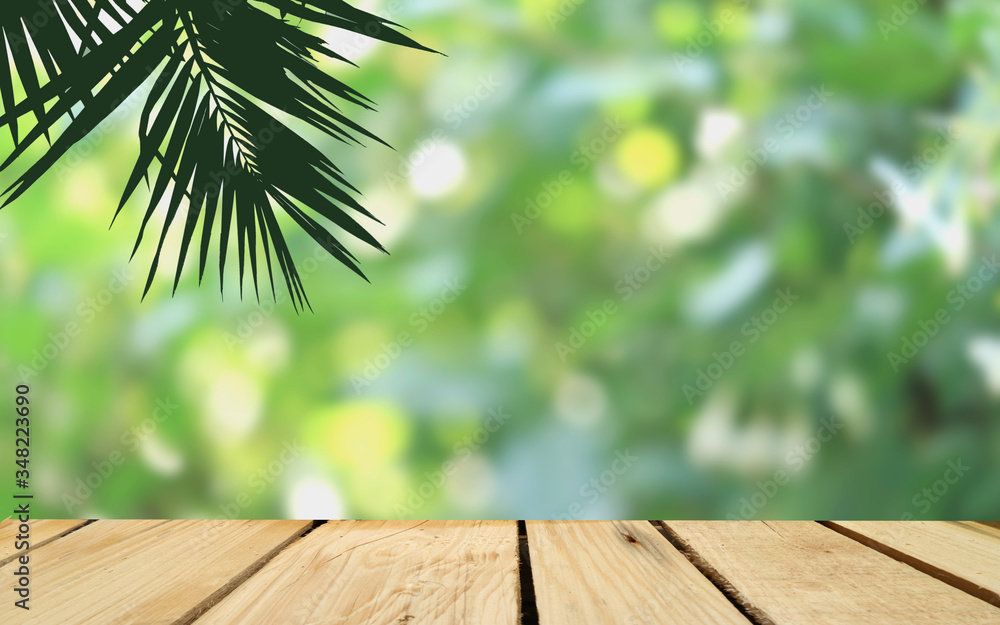 silhouette of plam tree and empty wood floor with bright bokeh of nature park background,product display montage. silhouette of plam tree and empty wood floor with bright bokeh of nature park background,product display montage.