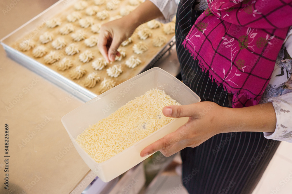 Obraz premium hand put a cheese topping on a cake. semprit traditional cake. kue semperit