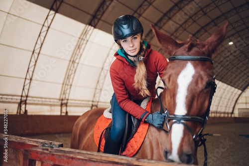 Pretty young woman riding a horse in the arena for equestrian sport