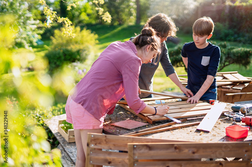 A mother and her two children build wooden planters for their permaculture vegetable garden