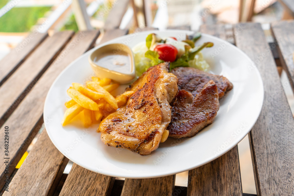 Meat plate of steaks and fries. Chicken and meat on a plate with potatoes in a summer cafe. Meat plate of steaks and fries. Chicken and meat on a plate with potatoes in a summer cafe.