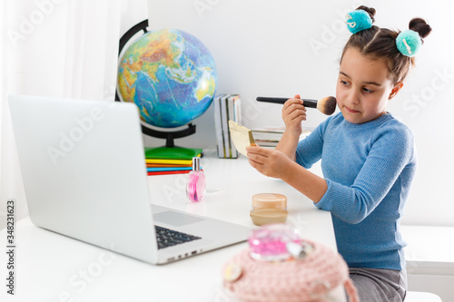 little girl learning make-up on laptop online, distance learning
