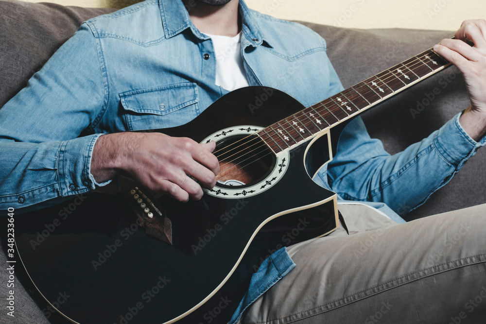 Obraz premium Man playing an black acoustic guitar