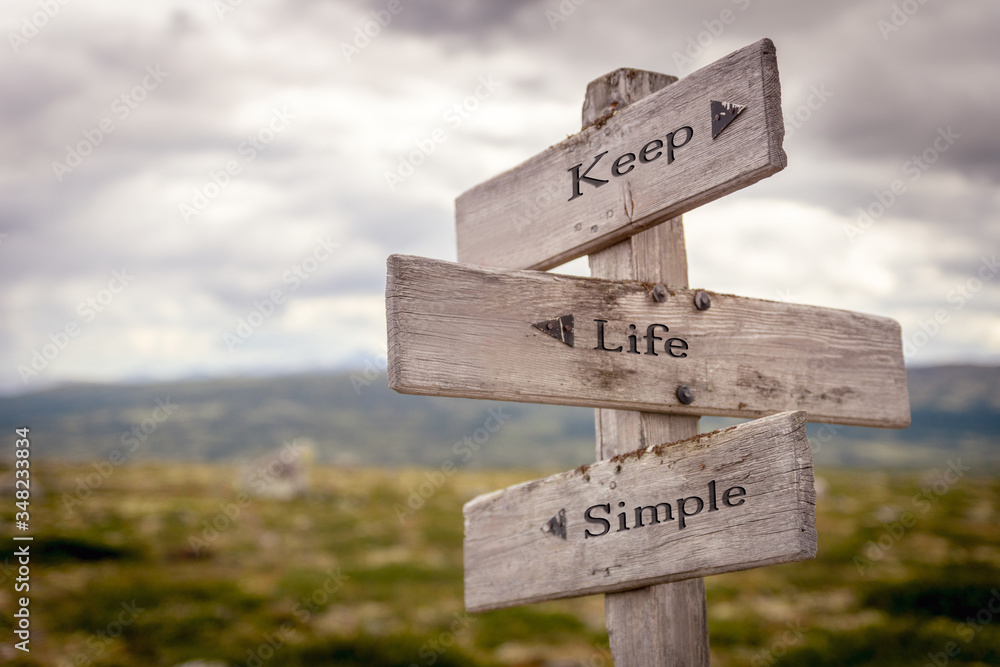 keep life simple text engraved on old wooden signpost outdoors in nature. Quotes, words and illustration concept.
