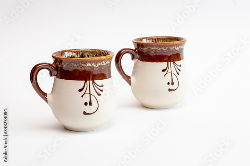 two beautiful decorated clay mugs isolated on a white background
