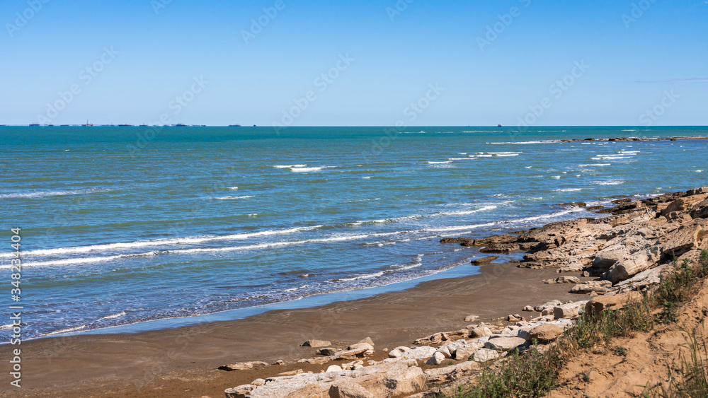 Rocky sea coast with blue water and small waves