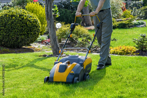Man cutting grass in his garden yard with lawn mower