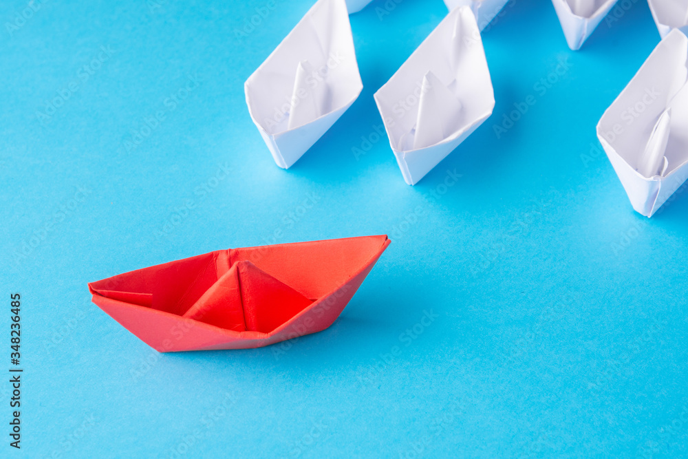 A red ship as a leader. White following it. Blue background. Place for text A red ship as a leader. White following it. Blue background. Place for text