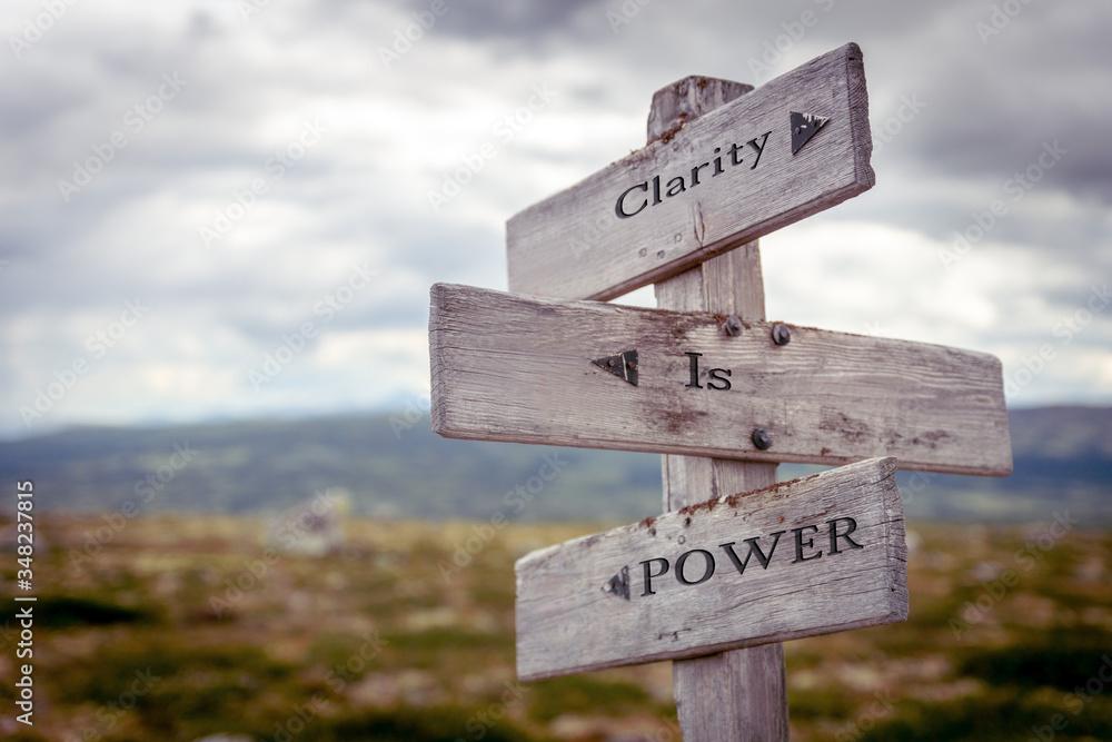 clarity is power text engraved on old wooden signpost outdoors in nature. Quotes, words and illustration concept.