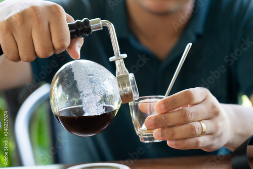 man pour black coffee from bottle to cup