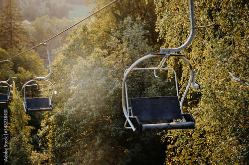 Chairlift in the mountain forest. Beautiful panorama view at sunny summer evening.
