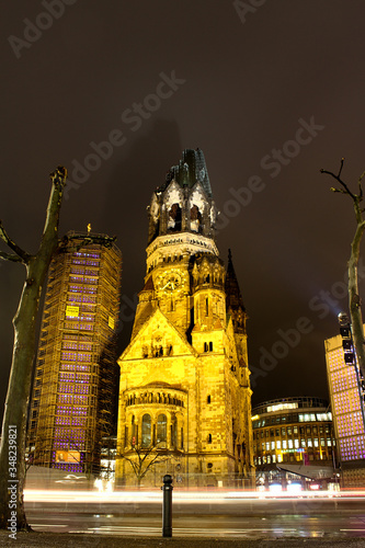Buildings in night city with lantern. German capital. Center of Berlin. Night life. Empty street with lighted buildings. Walking through the street. Deep blue sky and gothic church.  Twilight.