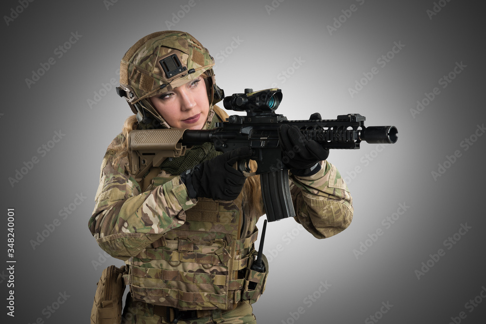 Fototapeta premium Female soldier in tactical black uniform with rifle. Shot in studio. Isolated with clipping path on grey background