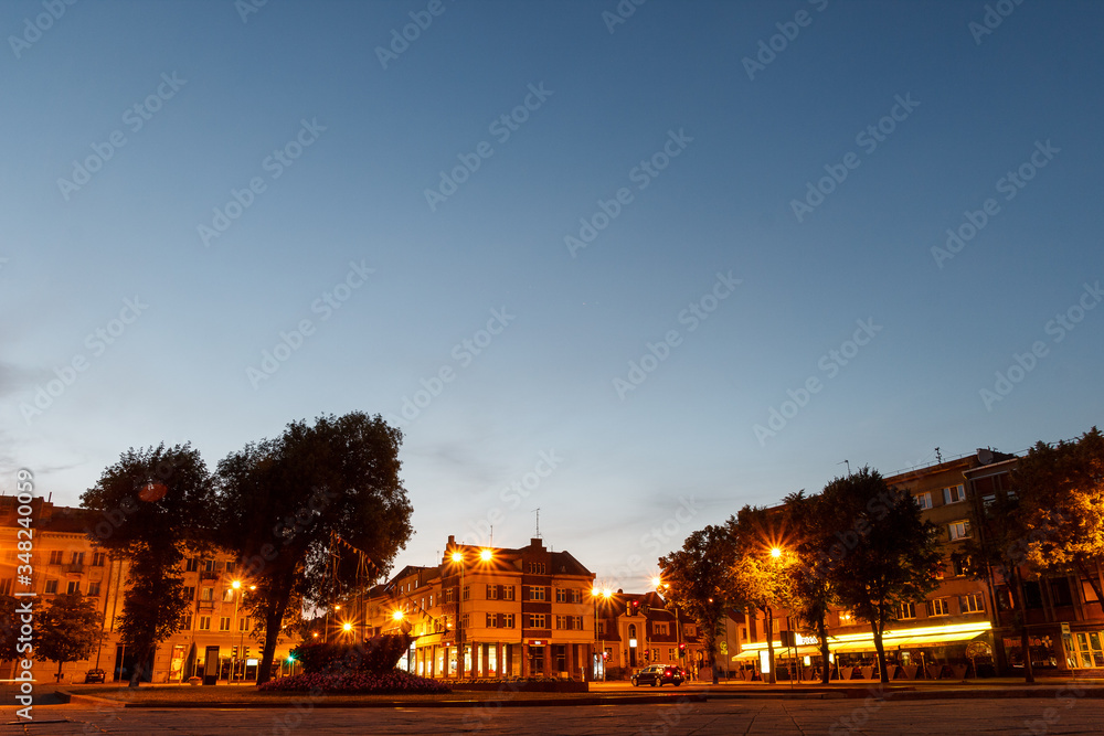 Buildings in night city with lantern. Lithuanian town. Center of Klaipeda. Night life. Empty street with lighted buildings. Walking through the street. Deep blue sky and historical house.  Twilight.