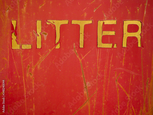 Yellow litter sign on a red metal surface with scratches.