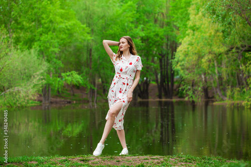 Portrait of a young beautiful woman in white dress posing by the lake