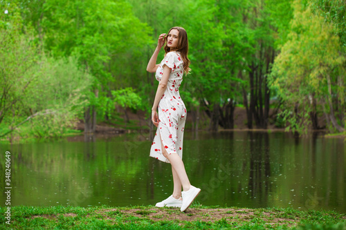 Portrait of a young beautiful woman in white dress posing by the lake