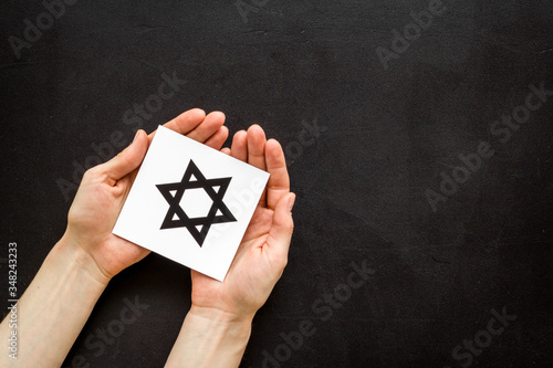 Star of David sign in hands - religion Judaisim symbol - on black table top view photo