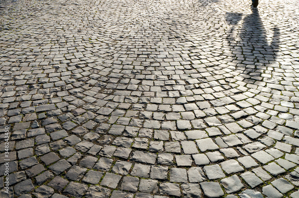 old cobblestone pavement close-up and lonely woman shadow walking home