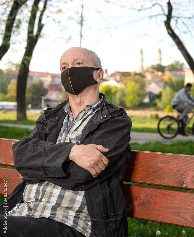 Senior man in protective face mask sitting on a bench Senior man in protective face mask sitting on a bench