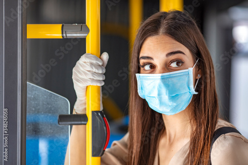 Woman wearing a sterile protective medical mask against coronavirus, Covid-2019 Asian pandemic sars virus while going in a public bus in a European city street looking ahead.