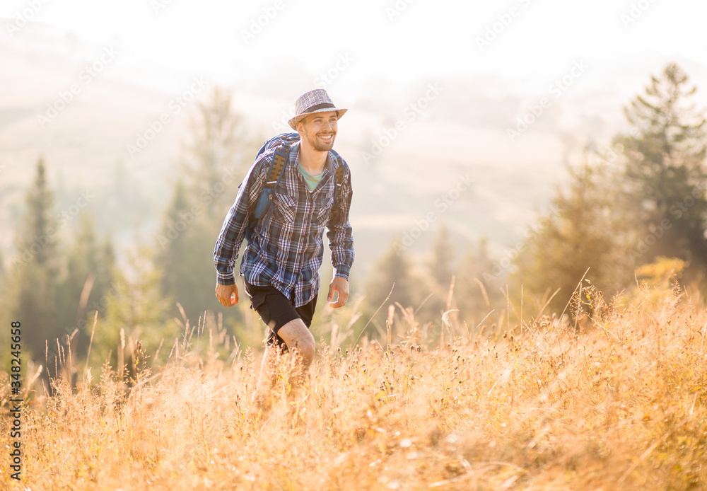 Bearded tourist man in hat with backpack hiking in mountains forest. Caucasian male hiker outdoors Bearded tourist man in hat with backpack hiking in mountains forest. Caucasian male hiker outdoors