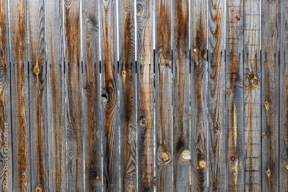 Background old wooden fence. Thin old planks are collected in a fence. Grey-brown texture of a rustic old fence. Background old wooden fence. Thin old planks are collected in a fence. Grey-brown texture of a rustic old fence.
