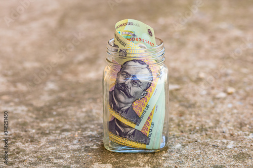 Composition with saving money romanian LEI banknotes in a glass jar. Concept of investing and keeping money, close up isolated. photo