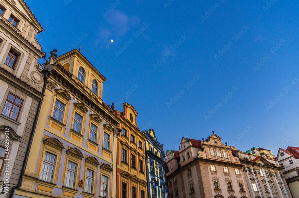 Row of buildings with colorful facades in Prague Old Town (Stare Mesto) historical city centre on Old Town Square Staromestske namesti in evening, blue sky and moon background, Bohemia, Czech Republic