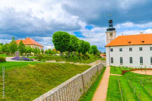 Jesuit College building, green grass lawn and green trees in Park GASK, Kutna Hora historical Town Centre, blue dramatic sky background, Central Bohemian Region, Czech Republic