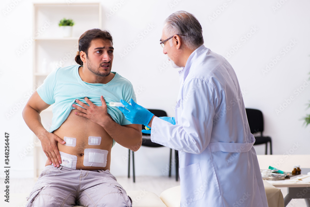 Obraz premium Injured young man visiting experienced male doctor