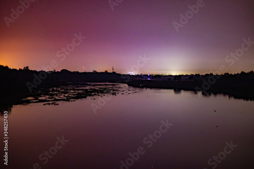 Night view of river side with little lights in the background of a town...