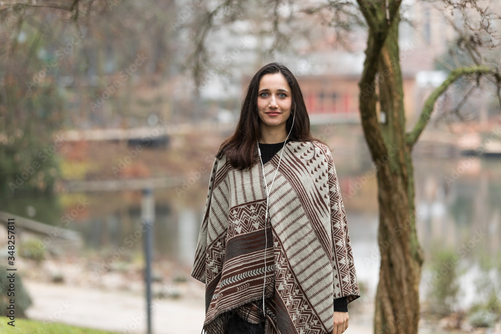 Beautiful Indian woman modeling in poncho for fall line outdoors. Looking at camera. Beautiful Indian woman modeling in poncho for fall line outdoors. Looking at camera.